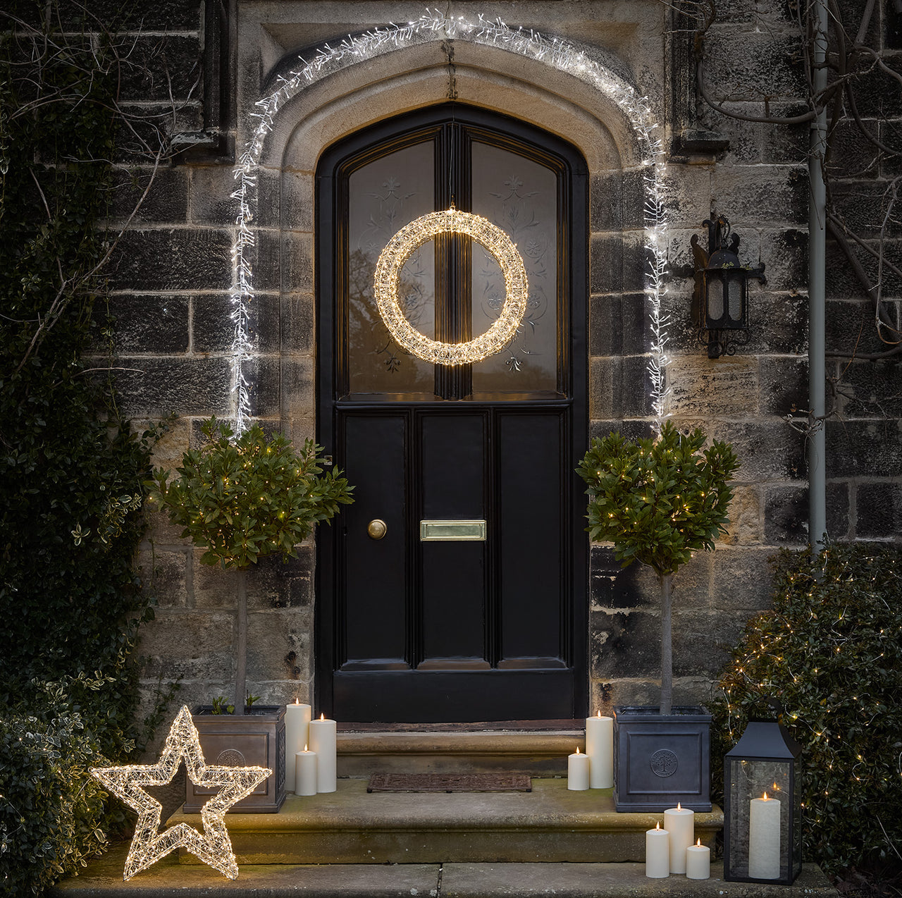 Wreath-garland-candles-star-lanterns-doorway-porch-potted-trees-steps.jpg